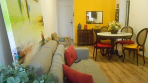 A living room with a sofa, a dining table with chairs, and a mirror on the wall. - Gohouse - Raul 1003 (Rio de Janeiro)