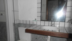 A bathroom with a toilet, sink, and mirror. - Gohouse - Suite Tonelero 03 (Rio de Janeiro)