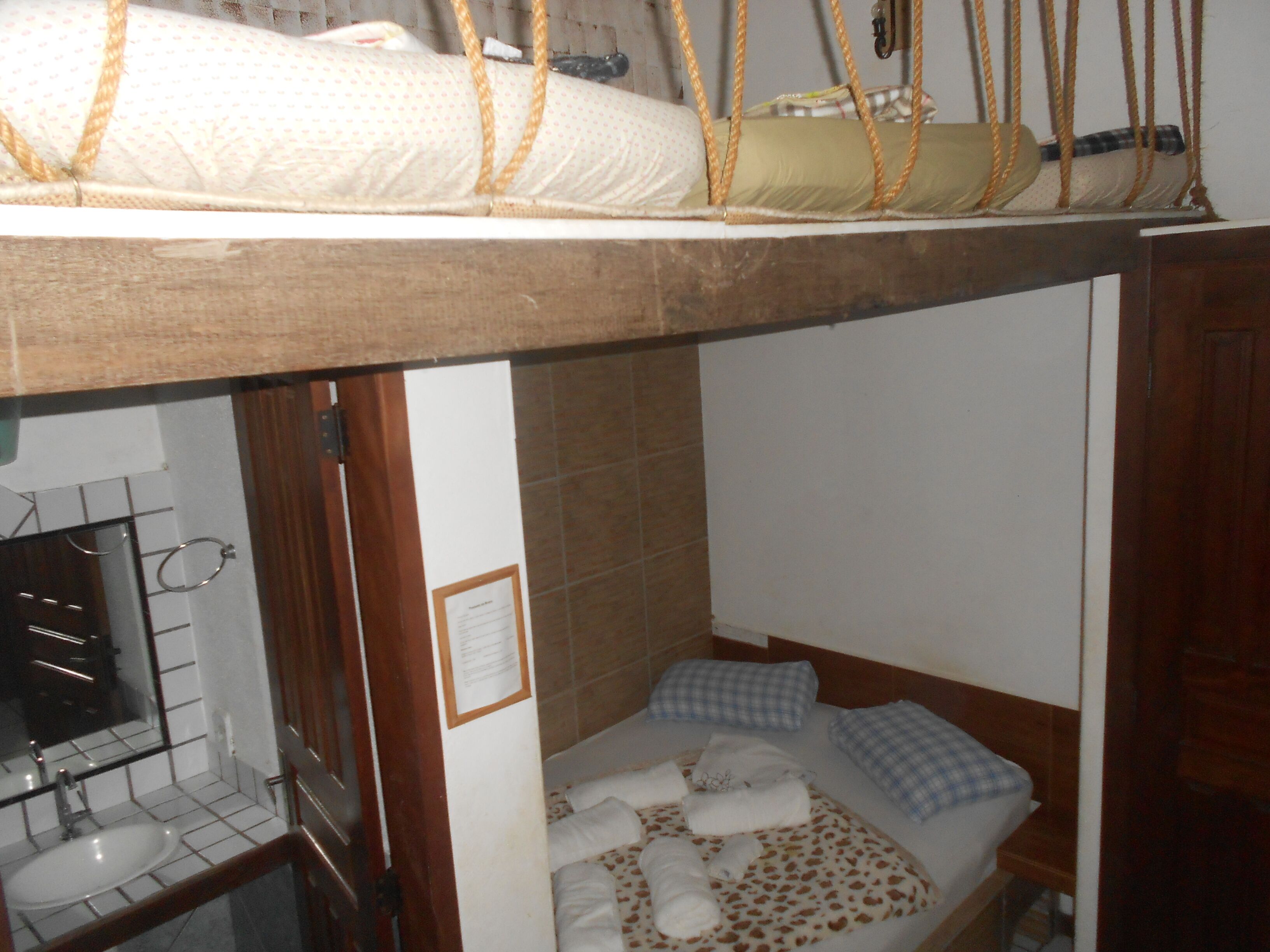 Un lit superposé avec une tête de lit en bois, une petite table de chevet et un miroir.