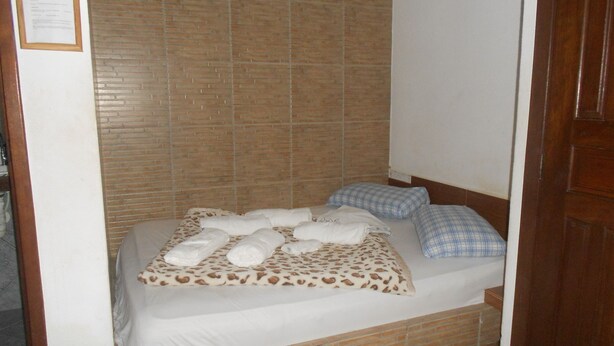 A small, single-bed room with a brick-patterned headboard, a white bedspread, and a few pillows. - Gohouse - Suite Tonelero 03 (Rio de Janeiro)