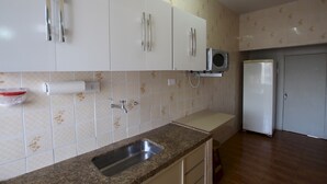 A kitchen with white cabinets, a granite countertop, a stainless steel sink, a microwave, and a refrigerator. - Gohouse - Rangel SP 96 (São Paulo)