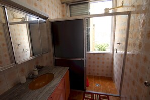 Une petite salle de bain comprenant un lavabo, un miroir et une douche.