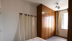 A bedroom with a bed, a wardrobe, a window with curtains, and a ceiling light fixture. - Gohouse - Rangel SP 96 (São Paulo)