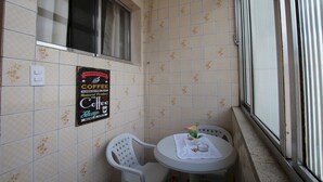 A small, tiled room with a window, a table with a chair, and a sign advertising coffee. - Gohouse - Rangel SP 96 (São Paulo)