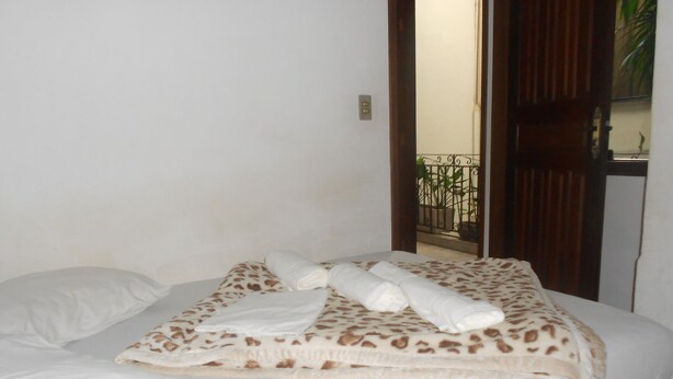 A neatly made bed with a patterned bedspread, a rolled towel, and a pillow. - Gohouse - Suite Tonelero 02 (Rio de Janeiro)