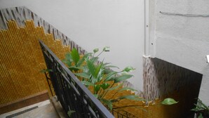 A staircase with a black metal railing, a bamboo wall, and green plants. - Gohouse - Suite Tonelero 02 (Rio de Janeiro)