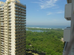 Ein Hochhaus mit mehreren Balkonen mit Blick auf eine Küstenregion, die dicht bewachsen ist und einen Strand umfasst.