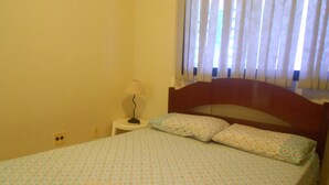 Una camera da letto con un letto, un comodino, una lampada e una finestra con persiane.