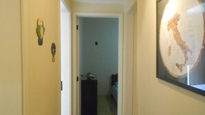 Un corridoio con una mappa incorniciata al muro, una porta che dà su una camera da letto e una piccola pianta a sinistra.