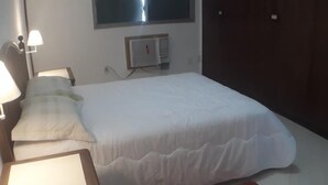 A bedroom with a bed, bedside lamps, a red rug, and a wall-mounted air conditioner. - Gohouse - Gomes 202 (Rio de Janeiro)
