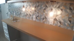 A reception desk with a geometric patterned wall, a telephone, and a light fixture. - Gohouse - Gomes 202 (Rio de Janeiro)