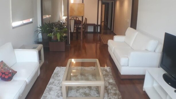 A modern living room with a glass coffee table, white sofas, and a TV on a stand. - Gohouse - Gomes 202 (Rio de Janeiro)