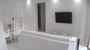 A modern, white bathroom with a large mirror, a mounted TV, and a glass-topped vanity. - Gohouse - Torre do Barao 108 (Rio de Janeiro)