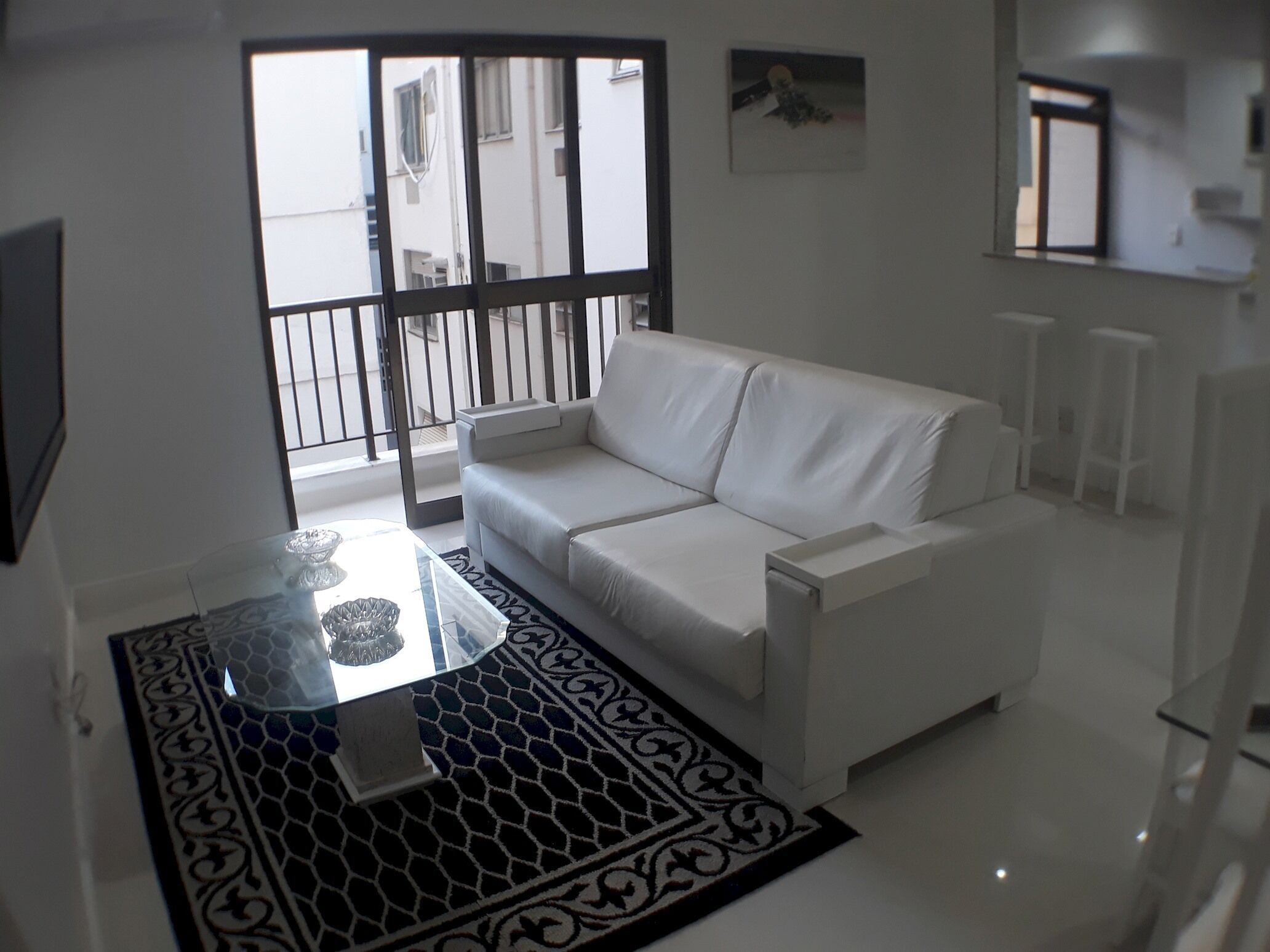 Ein modernes Wohnzimmer mit einem weißen Sofa, einem Glastisch und einem gemusterten Teppich.