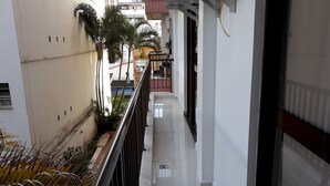 A narrow corridor with a metal railing, white walls, and a tiled floor. - Gohouse - Torre do Barao 108 (Rio de Janeiro)
