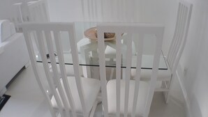 A white dining area with a glass table and white chairs. - Gohouse - Torre do Barao 108 (Rio de Janeiro)