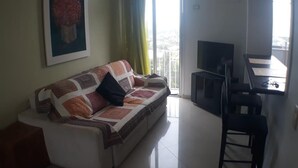 Un saló amb un sofà, una televisió i un balcó amb vistes.