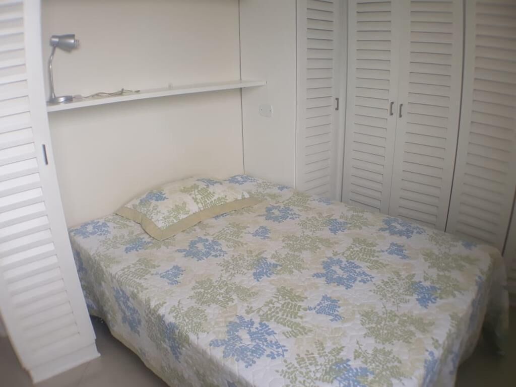 A bedroom with a bed, a shelf, and a wardrobe.