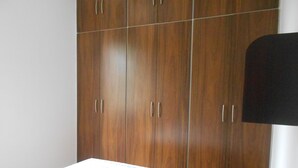 A bedroom with a bed, a wooden wardrobe, and a black headboard. - Gohouse - Torre 302 C (Rio de Janeiro)