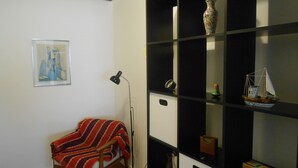 A room with a bed, a floor lamp, a shelf with decorative items, and a framed picture on the wall. - Gohouse - Torre 302 C (Rio de Janeiro)