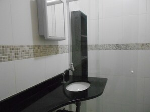 A bathroom with a black sink, a mirror, and tiled walls.
