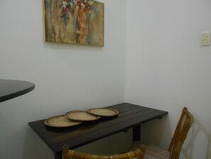 A dining area with a table, chairs, and a wall-mounted painting.