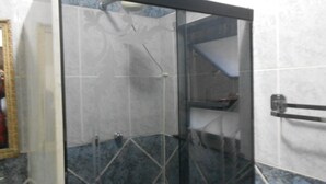 Une salle de bain avec une douche à parois de verre, un porte-serviettes et un miroir.