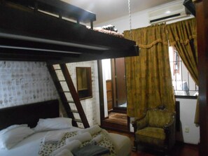 A bunk bed with a ladder, a chair, and a window with curtains. - Gohouse - Suite Tonelero 05 (Rio de Janeiro)