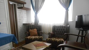 A living room with two patterned armchairs, a coffee table, a television, and a patterned rug.