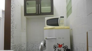 A kitchen with a microwave on top of a refrigerator, a sink, and cabinets above the counter.