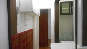 A narrow hallway with a tiled floor, a red patterned curtain, a white door, and a white cabinet.