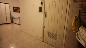 Una stanza con una porta bianca, una piccola finestra e un pavimento piastrellato.