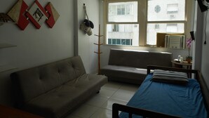 A room with a bed, a sofa, and a window with a view of buildings. - Gohouse - Copacabana 402 (Rio de Janeiro)