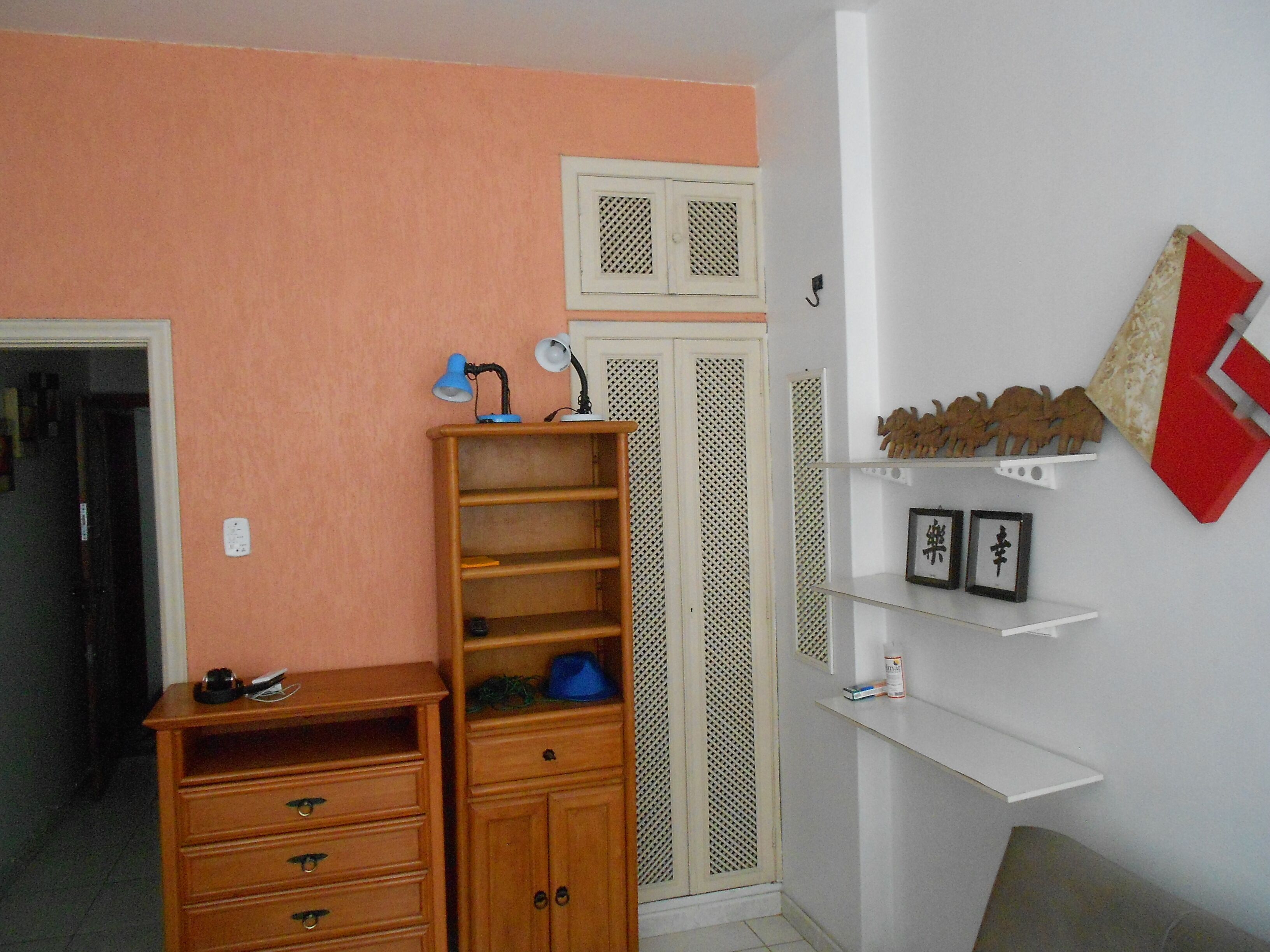 Une pièce comprenant une commode en bois, une armoire et une étagère blanche ornée d’objets décoratifs.