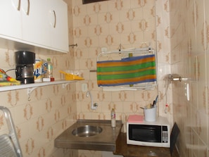 Kitchen area with a stainless steel sink, microwave oven, and white cabinets with silver handles.