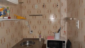 A small kitchenette with a sink, a microwave, and a shelf with kitchen items. - Gohouse - Copacabana 402 (Rio de Janeiro)