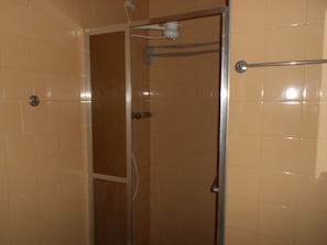 Ein Badezimmer mit beigen Fliesen, einer Duschkabine und einem Handtuchhalter.
