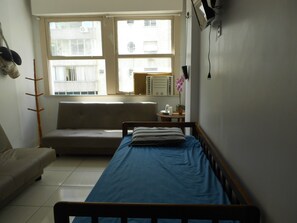 Cozy retreat with a single bed, sofa, and table, perfect for a relaxing stay.
