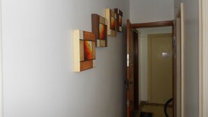 A hallway with a wooden door and a set of three framed artworks on the wall. - Gohouse - Copacabana 402 (Rio de Janeiro)