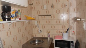A small kitchen with a sink, a microwave, a coffee maker, and a shelf with various items. - Gohouse - Copacabana 402 (Rio de Janeiro)