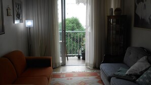 A living room with an orange sofa, a grey sofa, a floor lamp, and a cabinet. - Gohouse - Loureiro 102 (Rio de Janeiro)