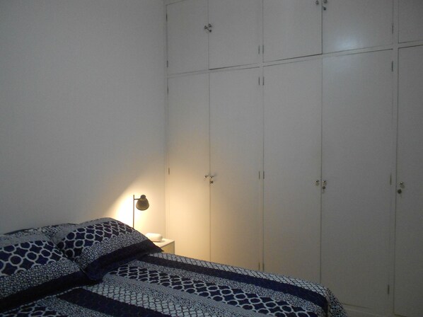Un dormitorio con una cama, una mesita de noche y un armario.