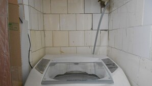 A compact, white, single-basin sink with a visible brand label, situated in a small, tiled room with a visible plumbing fixture above. - Gohouse - Sacadura 601 (Rio de Janeiro)
