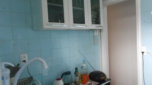 A kitchen with blue tiles, a white cabinet with three windows, a sink with a hose, and various kitchen items on the counter. - Gohouse - Sacadura 601 (Rio de Janeiro)