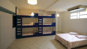 A dormitory room with bunk beds, a single bed, a window, and an air conditioning unit. - Gohouse - Visconde 206 (Rio de Janeiro)