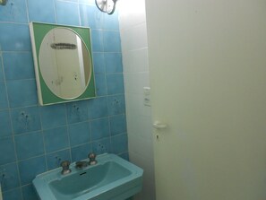 A bathroom with blue tiles, a white sink, and a mirror. - Gohouse - Siqueira 1003 (Rio de Janeiro)