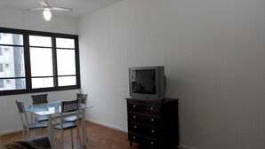 A room with a dining table and chairs, a television on a dresser, and a ceiling fan. - Gohouse - Siqueira 1003 (Rio de Janeiro)