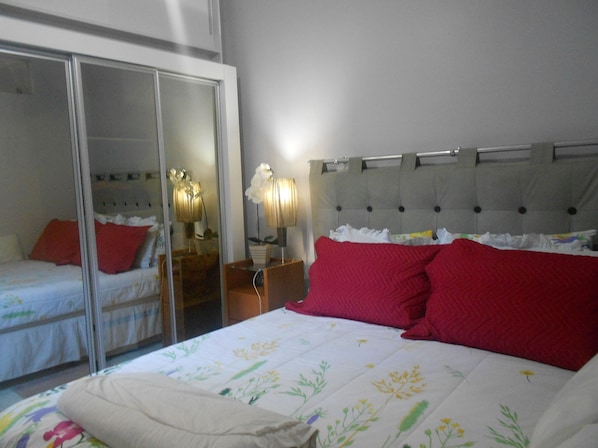 A bedroom with a bed, a wardrobe, and a nightstand with a lamp.