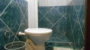 A bathroom with a toilet, a shower curtain, and a tiled wall. - Gohouse - Suite Tonelero 01 (Rio de Janeiro)
