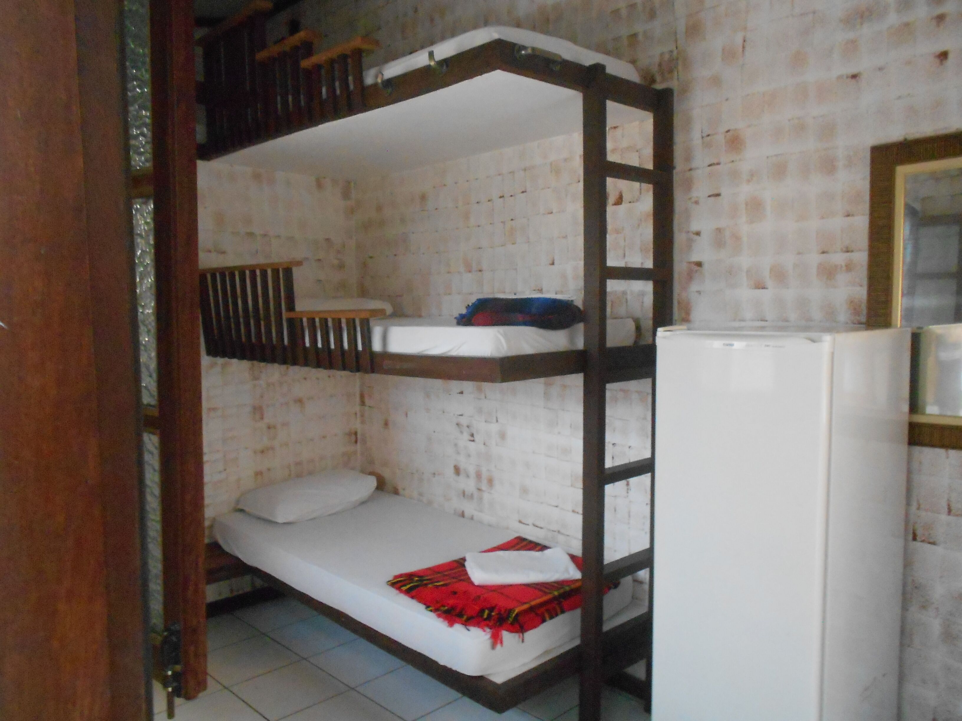 A bunk bed room with a white refrigerator and a wooden ladder.